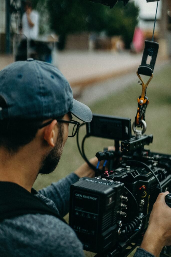 pexels-photo-2773498-2773498 A focused filmmaker operating a cinema camera outdoors during daylight, capturing a creative video shoot.